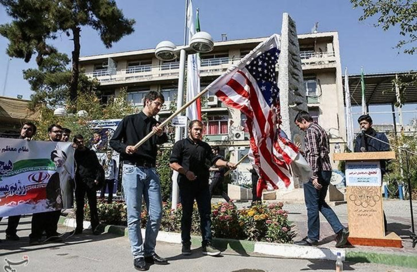  Iranian students burn a US flag during a protest. (photo credit: TASNIM NEWS AGENCY/HANDOUT VIA REUTERS)