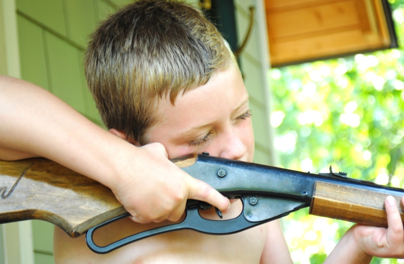 A young boy aiming a BB gun (photo credit: INGIMAGE)