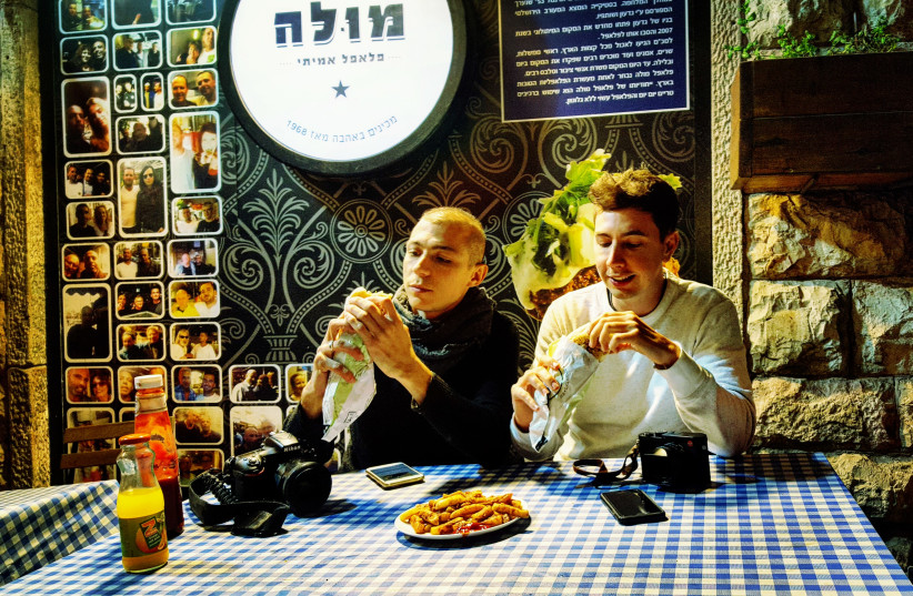 Famous South African photographers Alexi Portokallis and Miklas Manneke experience their first Israeli falafels in Mahane Yehuda on Saturday night (photo credit: ILANIT CHERNICK)
