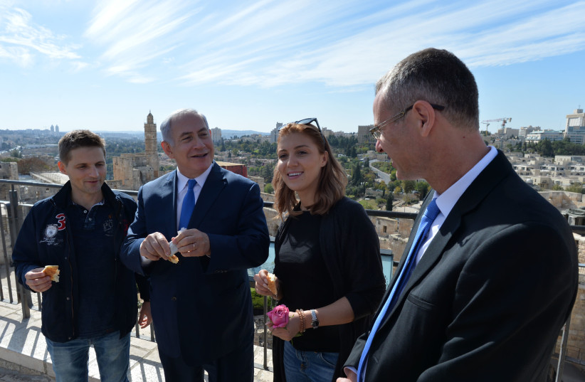 Prime Minister Benjamin Netanyahu (center-left) and Tourism Minister Yariv Levin (right) welcome the 3 millionth tourist, Romanian couple Ioana Isac (center-right) and Mihai Georgescu (left) (photo credit: KOBI GIDEON/GPO)