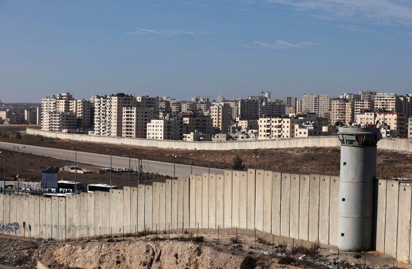 A view shows the Israeli barrier as buildings are seen in Kfar Aqab on the outskirts of Jerusalem, near the West Bank City of Ramallah, November 7, 2017. (credit: REUTERS/MOHAMAD TOROKMAN)
