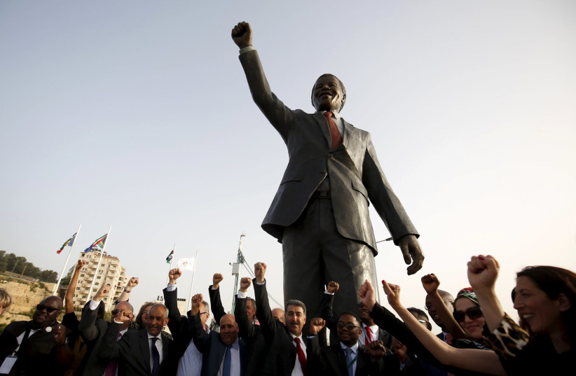 People cheer in front of a Mandela statue during the inauguration of Nelson Mandela Square in the West Bank city of Ramallah (photo credit: MOHAMAD TOROKMAN/REUTERS)