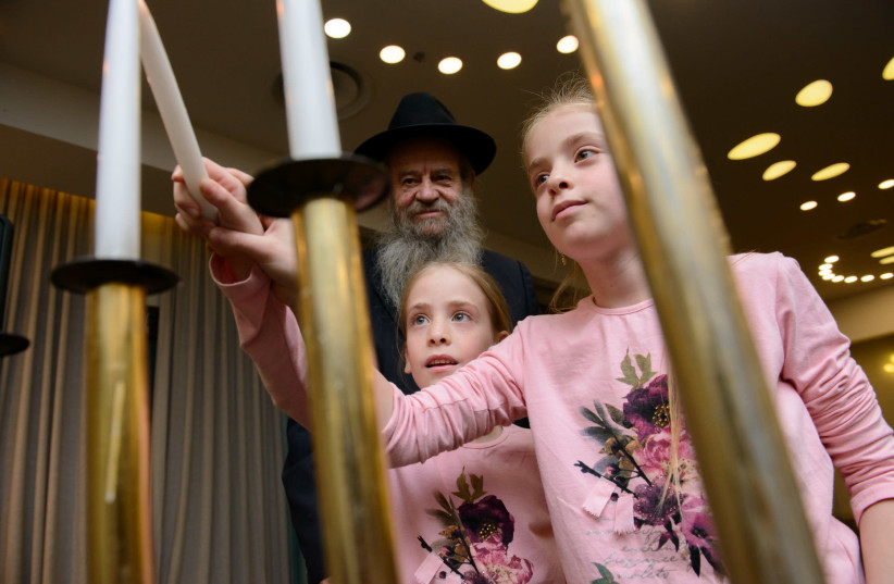 Rabbi Amram Blau, director of the Chessed Menachem Mendel program of Colel Chabad lights candles with some of the younger participants in the annual retreat for widows and their children (photo credit: MOSHE BUKHMAN)
