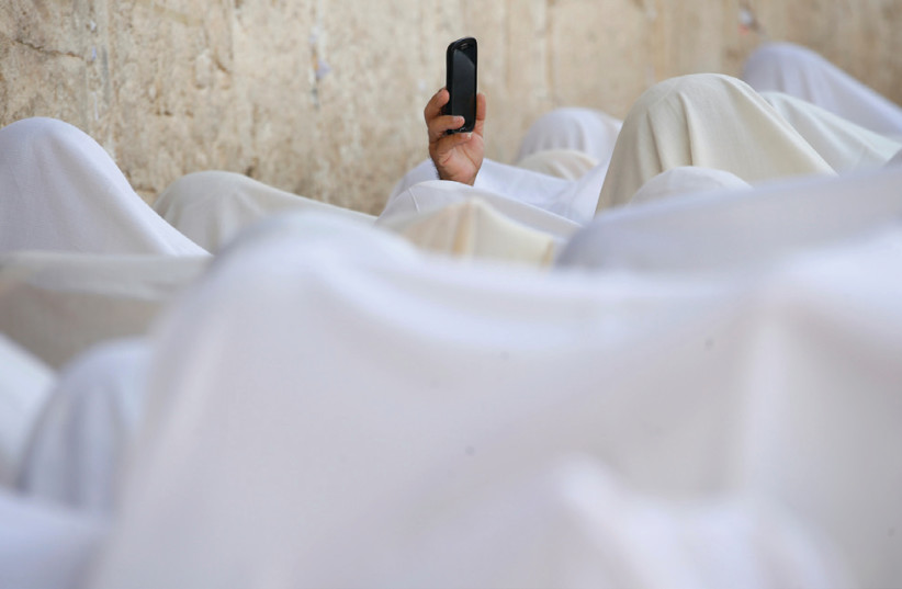 A man holds up a cellphone during the priestly blessing at the Western Wall (photo credit: BAZ RATNER/REUTERS)