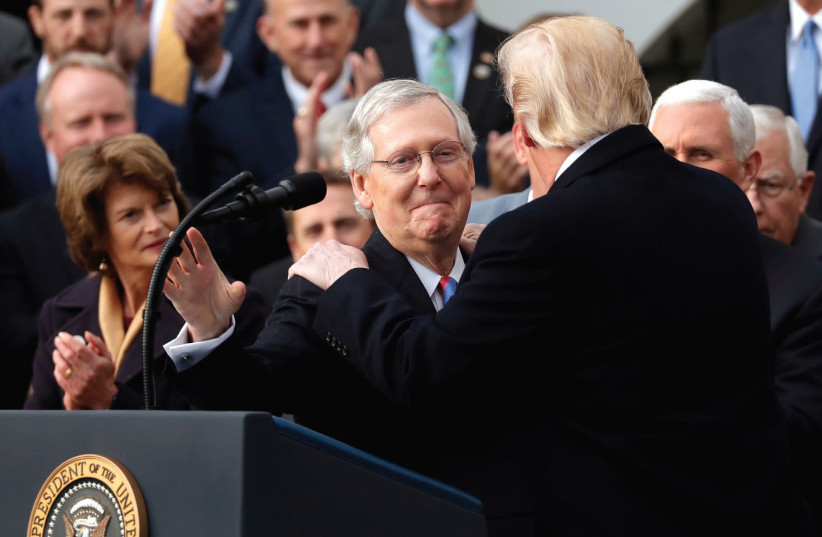 US PRESIDENT Donald Trump celebrates with Republican Majority Leader Mitch McConnell and other Congressional Republicans after the US Congress passed sweeping tax overhaul legislation in December. (photo credit: REUTERS)