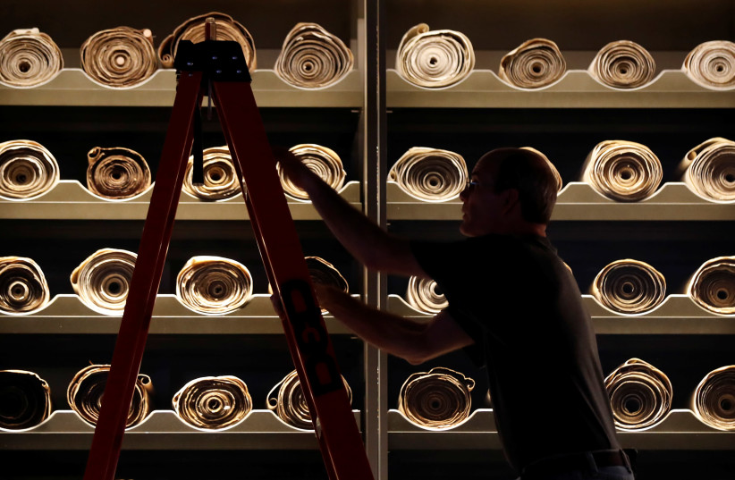 A worker climbs a ladder beside Torah scrolls on display at the Museum of the Bible in Washington, U.S. (photo credit: REUTERS)