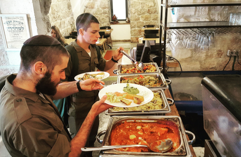 Two American lone soldiers dish-up food during a Friday buffet at Piccolino restaurant in Jerusalem.  (photo credit: ILANIT CHERNICK)