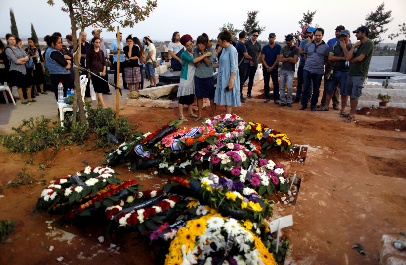 Family and friends mourn around the fresh graves of Haya, Elad and Yossi, three members of the Salomon family who were killed in a stabbing attack Friday night in the Jewish settlement of Neve Tsuf (photo credit: RONEN ZVULUN / REUTERS)