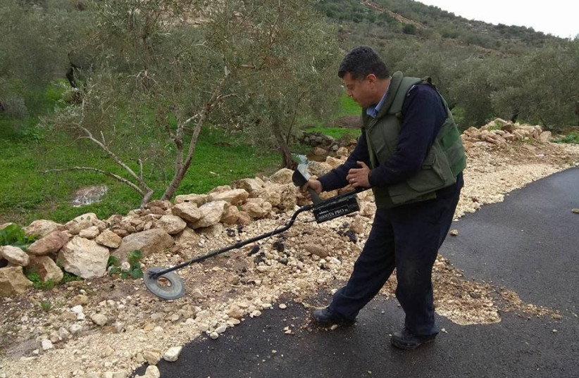 A Palestinian Authority policeman uses a metal detector while searching for explosive devices in the West Bank, January 2018 (photo credit: COURTESY PALESTINIAN AUTHORITY POLICE)