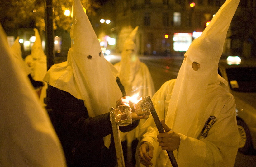 Supporters dressed as members of the Ku Klux Klan light flares as they express antisemitic views in Ukraine (photo credit: VASILY FEDOSENKO / REUTERS)