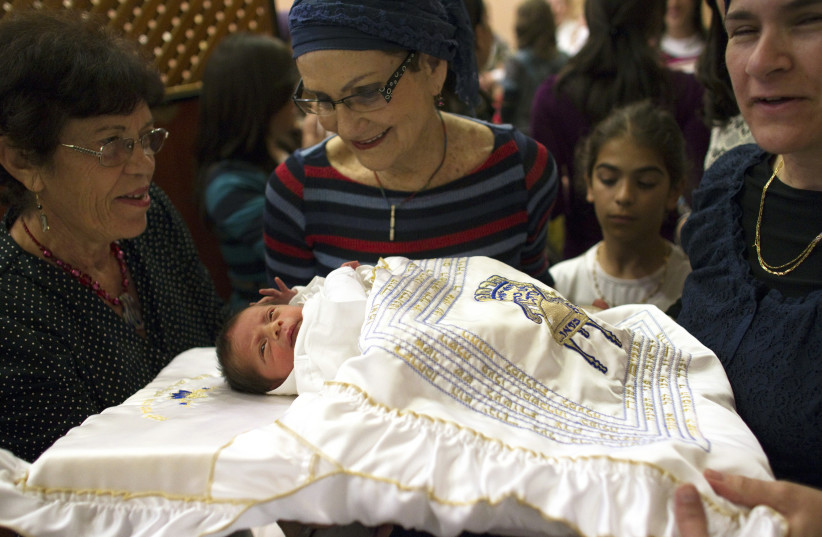 Relatives look at a baby after his circumcision in Jerusalem September 24, 2012. (photo credit: REUTERS/Ronen Zvulun)