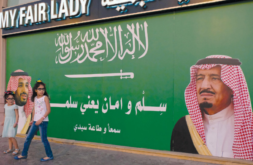 GIRLS STAND next to a poster depicting Saudi Arabia’s King Salman bin Abdulaziz Al Saud (right) and Crown Prince Mohammed bin Salman in Jeddah, Saudi Arabia, 2017.  (photo credit: REUTERS/REEM BAESHEN)