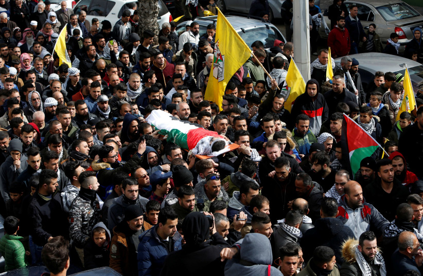 Mourners carry the body of Palestinian assailant Hamza Zamarah, during his funeral in Halhoul, in the West Bank February 17, 2018. (photo credit: REUTERS/MUSSA QAWASMA)