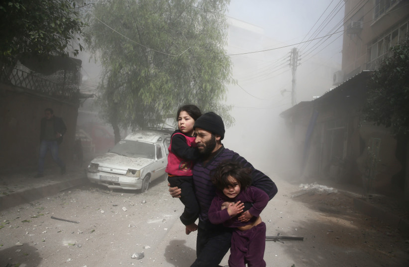 A man runs amid dust after an airstrike in the besieged town of Douma in eastern Ghouta in Damascus, Syria (credit: REUTERS/BASSAM KHABIEH)