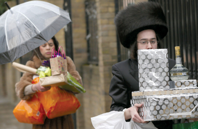 HAMAN RECOGNIZES His Fate’ (produced between 1648 and 1665) by either the famed Dutch painter Rembrandt or his workshopMEMBERS OF the Jewish community carry gifts as they celebrate Purim in London in 2016 (photo credit: NEIL HALL/REUTERS)