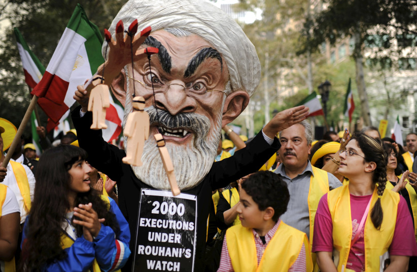 Max Saatchi stands with other protesters while wearing a mask depicting Iranian President Hassan Rouhani during a "No to Rouhani, Yes to Human Rights in Iran Rally" organized by the National Council of Resistance to Iran, outside the United Nations headquarters in Manhattan, New York, September 28,  (photo credit: DARREN ORNITZ / REUTERS)