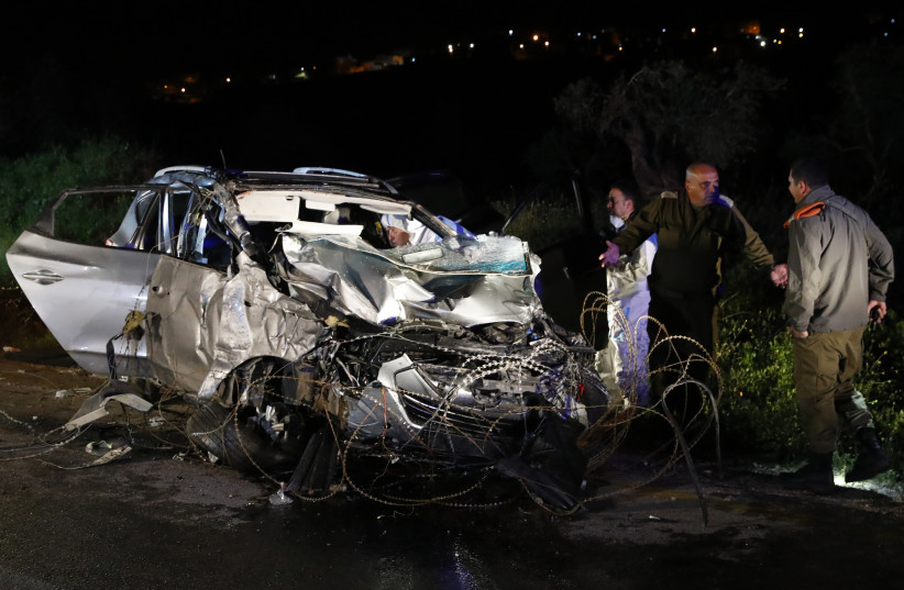 Israeli security forces and forensics inspect the destroyed vehicle that was used by a Palestinian assailant in a car ramming attack in the West Bank on March 16, 2018.  (photo credit: JACK GUEZ / AFP)