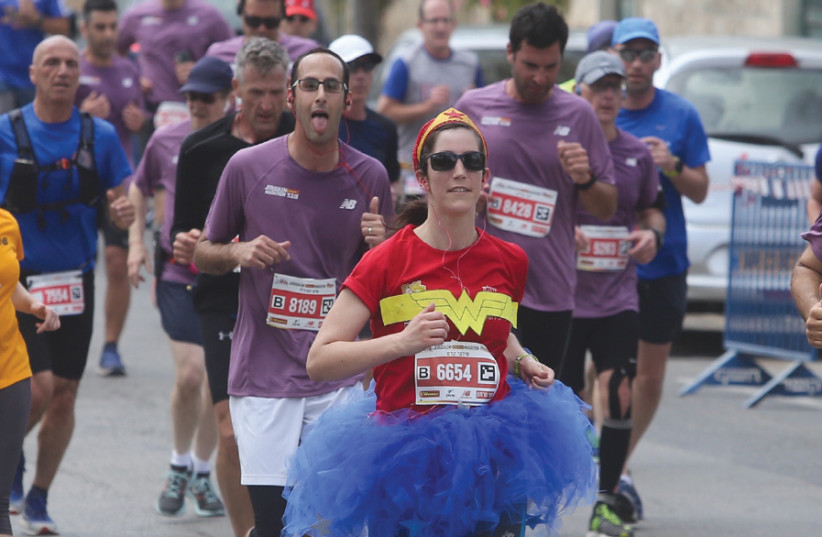 An athlete dressed as Wonder Woman runs in the Jerusalem Marathon on March 9 (photo credit: MARC ISRAEL SELLEM)