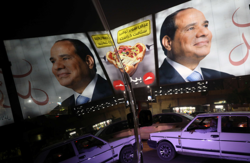 People walk in front of banners with Egypt's President Abdel Fattah al-Sisi during preparations for the presidential election in Cairo, Egypt (photo credit: AMMAR AWAD/REUTERS)