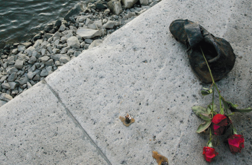 ROSES ARE placed on a bronze sculpture of a shoe on the banks of the River Danube in Budapest, part of a memorial to the thousands of Hungarian Jews shot into the river during the Holocaust (photo credit: KAROLY ARVAI/REUTERS)