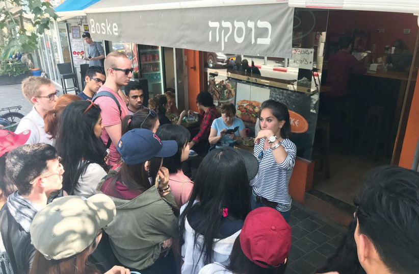 Tech tourists listen to a guide in Tel Aviv’s Carmel Market (photo credit: Courtesy)