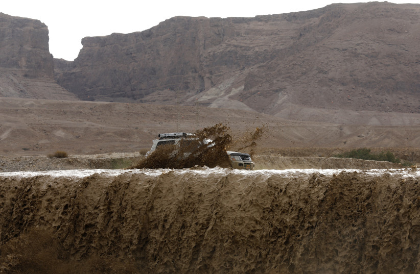 Flooded water running through a valley in the Judean desert following heavy rainfall in the mountains on April 25, 2018.  (photo credit: MENAHEM KAHANA / AFP)