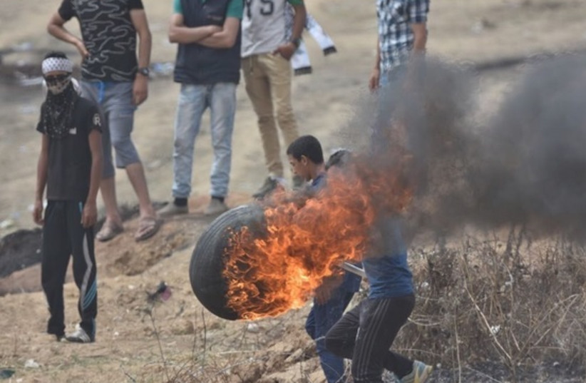 Palestinian protester with a burning tire  (photo credit: IDF SPOKESMAN’S UNIT)