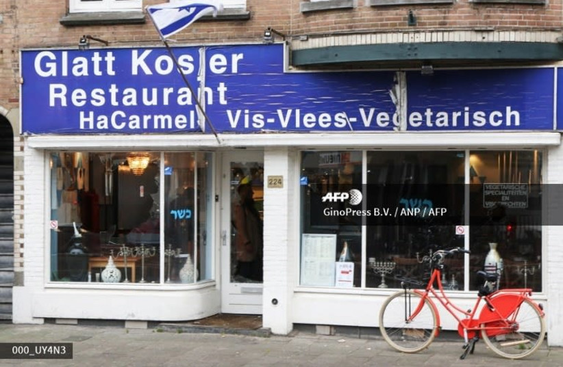 The damaged storefront of kosher Jewish restaurant HaCarmel in Amsterdam. A man, shown holding a Palestinian flag in video footage released on local media sites, smashed the windows of the restaurant (photo credit: GINOPRESS B.V./ ANP / AFP)