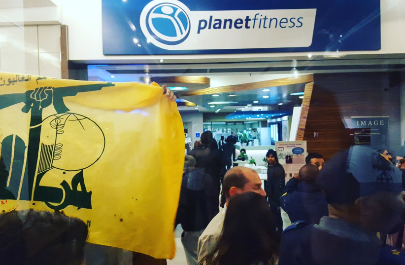 BDS supporters fly a Hezbollah flag during a protest at the #YallaYebo photo exhibition, May 31, 2018 (photo credit: ILANIT CHERNICK)