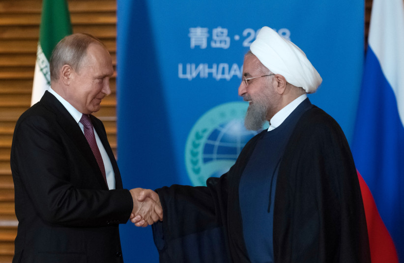 Russian President Vladimir Putin (L) shakes hands with Iranian President Hassan Rouhani during a meeting on the sidelines of the Shanghai Cooperation Organisation Summit (SCO) in Qingdao, China June 9, 2018.  (photo credit: SPUTNIK/SERGEI GUNEEV/KREMLIN VIA REUTERS)