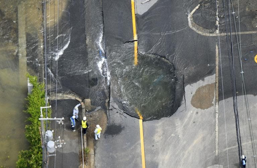 Water flows out from cracks in a road damaged by an earthquake in Takatsuki, Osaka prefecture, western Japan, in this photo taken by Kyodo June 18, 2018. (photo credit: KYODO/VIA REUTERS)