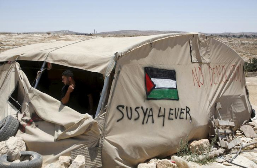 A Palestinian man looks out of a tent in Sussiya village, south of the West Bank city of Hebron July 20, 2015 (photo credit: MUSSA QAWASMA / REUTERS)