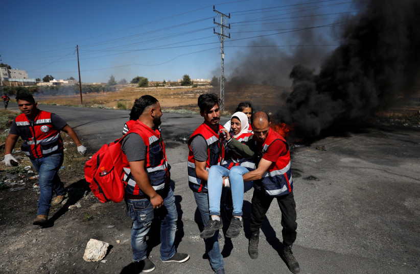 Wounded Palestinian medic is evacuated during clashes with Israeli troops at a protest near the Jewish settlement of Beit El, near Ramallah (photo credit: MOHAMAD TOROKMAN/REUTERS)