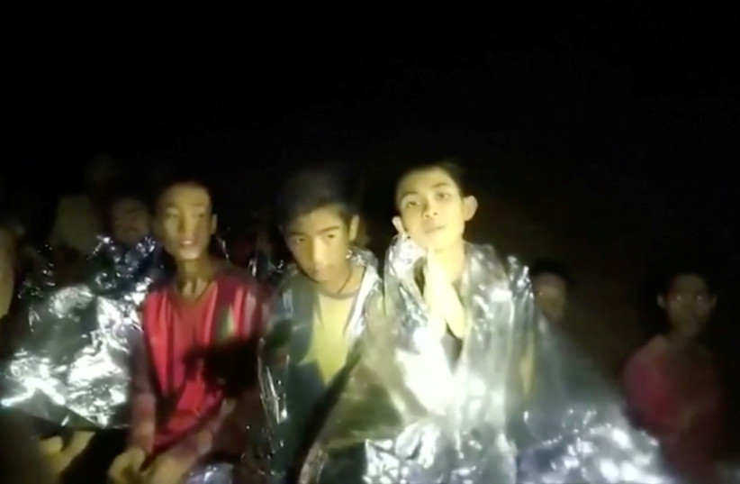 Boys trapped inside Tham Luang cave greet members of the Thai rescue team, in this still image taken from a July 3, 2018 video by Thai Navy Seal (photo credit: THAI NAVY SEAL/HANDOUT VIA REUTERS TV)