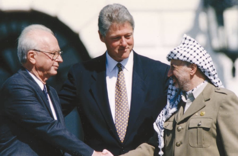 PLO Chairman Yasser Arafat (right) shakes hands with Israeli Prime Minister Yitzhak Rabin (left), as U.S. President Bill Clinton stands between them, after the signing of the Israeli-PLO peace accord, at the White House in Washington, on September 13, 1993 (photo credit: GARY HERSHORN/REUTERS)