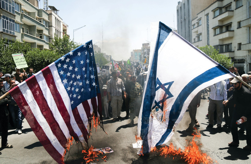 IRANIANS BURN US and Israeli flags during a protest in Tehran in June (photo credit: TASNIM NEWS AGENCY/HANDOUT VIA REUTERS)
