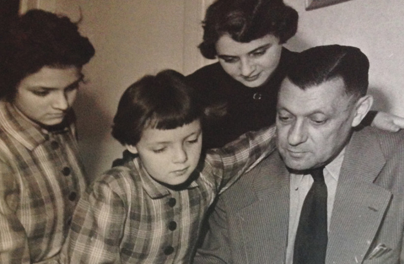 Jana and her sister Eva with their parents, at her father’s newspaper office in Prague, in 1958, reflected in the glass of his desk (photo credit: Courtesy)