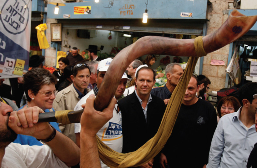 A man blows a shofar during mayoral candidate Nir Barkat’s visit to Jerusalem’s Mahane Yehuda market on November 6, 2008 (photo credit: BAZ RATNER/REUTERS)