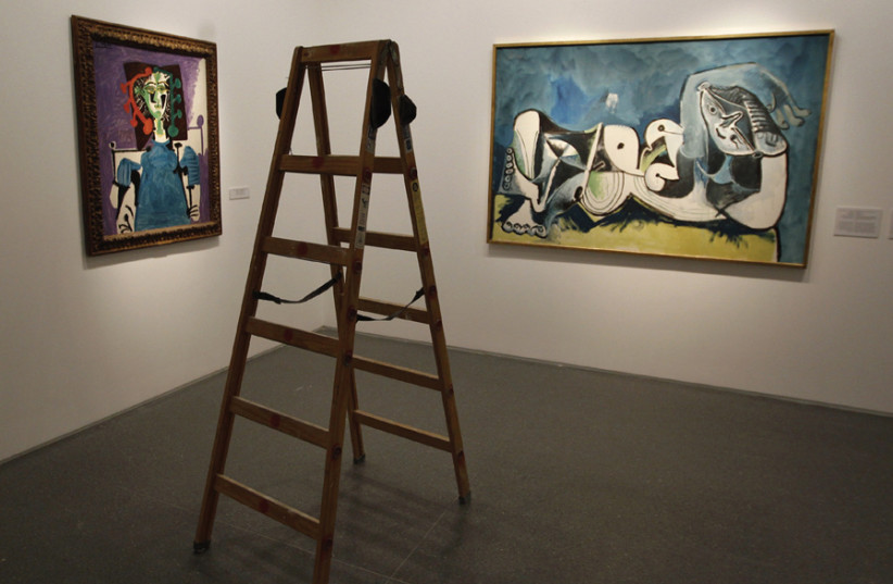 A ladder stands in front of two paintings by Pablo Picasso at the Israel Museum in Jerusalem; Picasso smashed the rules of painting and sculpture (photo credit: REUTERS/KAI PFAFFENBACH)