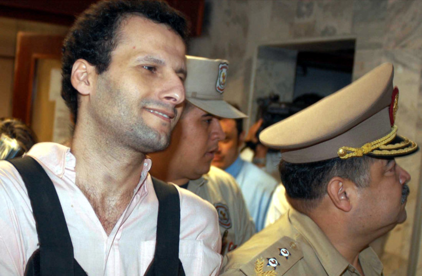 Lebanese-born businessman Assad Ahmad Barakat, a suspected member and fund-raiser of the Islamic group Hizbollah, leaves the Justice building under escort of police officers in Asuncion, November 18, 2003. Barakat, who was extradited from Brazil to Paraguay, is accused by Paraguayan authorities of f (photo credit: MIGUEL MASCARENO/ REUTERS)