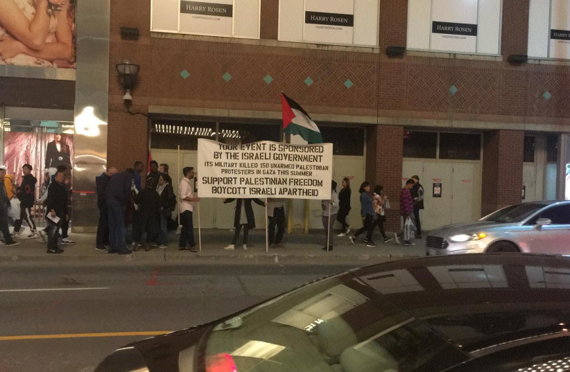 PROTESTERS HOLD a sign outside the Gesher Theater's show in Toronto over the weekend (photo credit: GESHER)