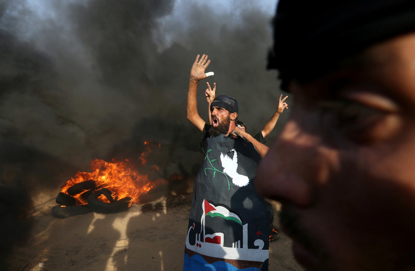 A Palestinian reacts during a protest calling for lifting the Israeli blockade on Gaza and demanding the right to return to their homeland, at the Israel-Gaza border fence in the southern Gaza Strip October 5, 2018.  (photo credit: IBRAHEEM ABU MUSTAFA / REUTERS)