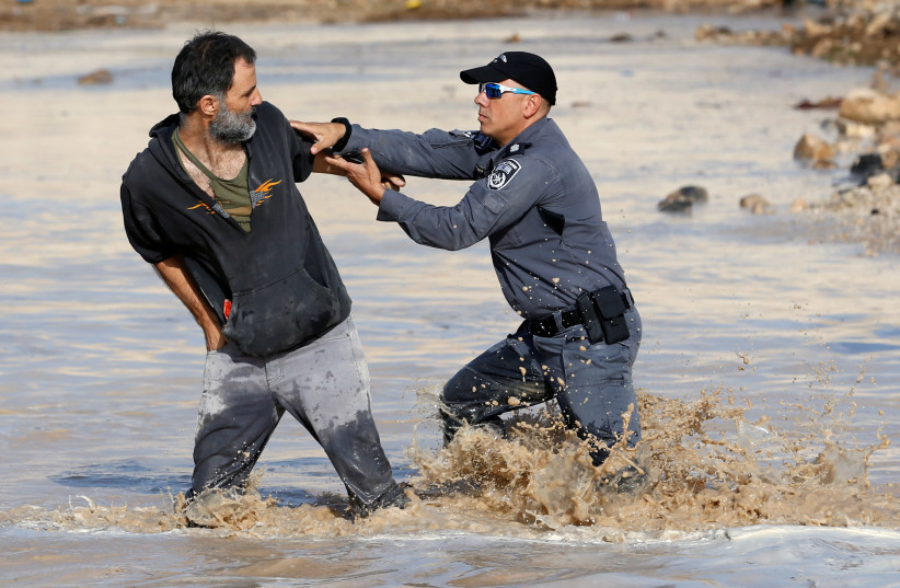 An Israeli police officer detains an activist in the illegal Palestinian Bedouin herding village of Khan al-Ahmar that Israel plans to demolish, in the West Bank. Clashes broke out there Monday when security forces arrived to drain a pool on the edge of the village, that had formed from a water leak (photo credit: MUSSA QAWASMA / REUTERS)