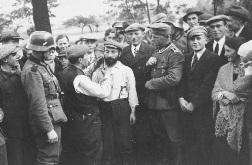 A GROUP of German soldiers and civilians look on as a Jewish man is forced to cut the beard of another in 1939. (photo credit: US HOLOCAUST MEMORIAL MUSEUM)