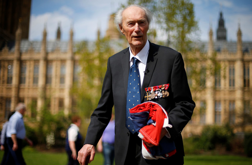  World War Two Norwegian resistance fighter Joachim Roenneberg holds up a Union flag, which had been lowered from above the House of Lords, after it was presented to him by the Clerk of the House of Lords in Westminster, London, April 25, 2013.  (photo credit: ANDREW WINNING/REUTERS)