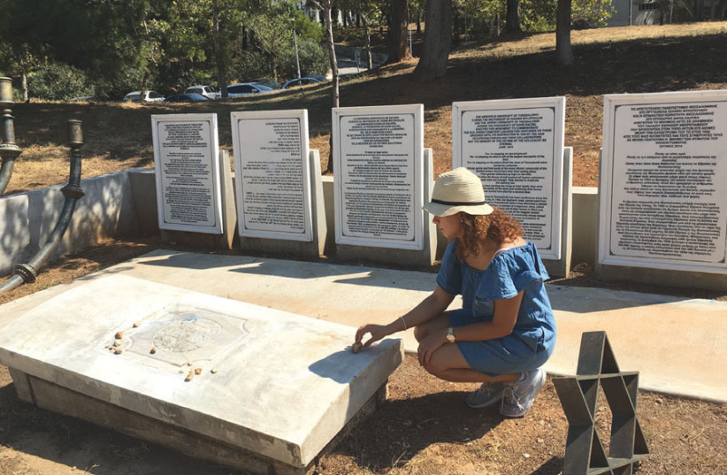 The writer places a stone on the memorial for the Jewish cemetery (photo credit: ORIT ARFA)