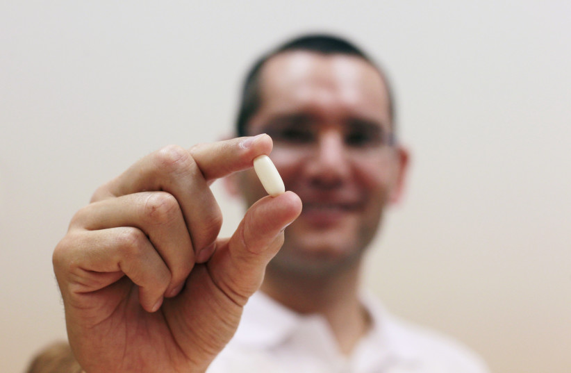 Nadav Kidron, CEO of Oramed Pharmaceuticals, shows an insulin pill as he poses for a photo at the company's offices in Jerusalem September 29, 2013. The insulin pill, long desired by diabetes doctors and patients but abandoned as not physically viable, could be available by the end of this decade as (photo credit: BAZ RATNER/REUTERS)
