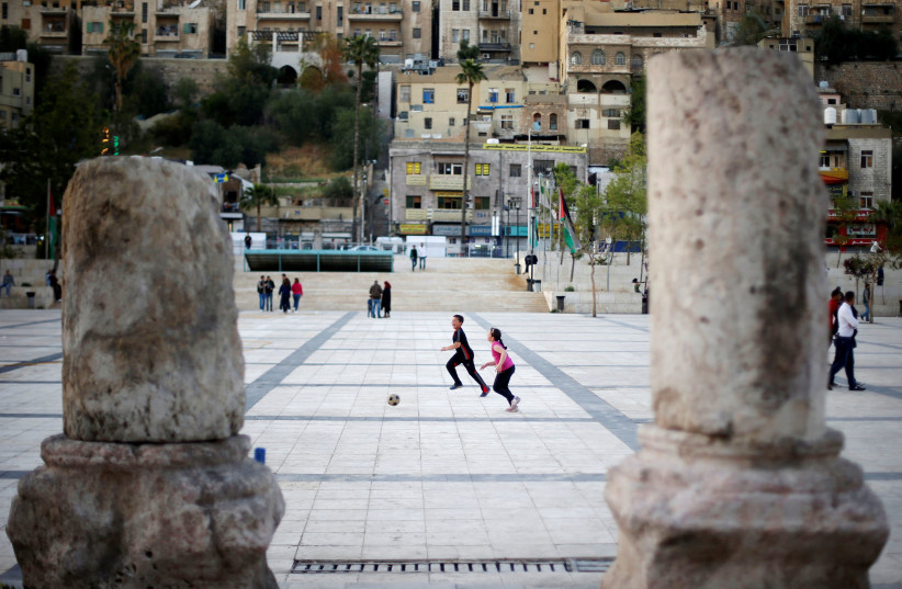 Children play football at the Roman Amphitheatre area in downtown Amman, Jordan April 1, 2018. (photo credit: REUTERS/MUHAMMAD HAMED)