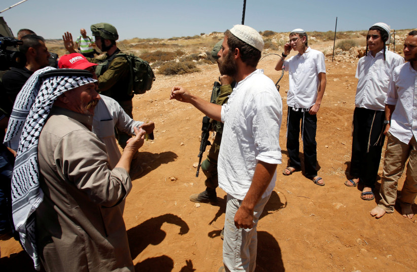 Palestinians argue with a Jewish settler during a protest against a new Jewish settlement outpost near Hebron, June 23, 2018 (photo credit: MUSSA QAWASMA / REUTERS)
