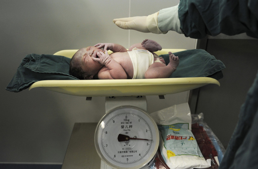 A newborn baby is weighed after it was born at a hospital in Hefei, Anhui province October 31, 2011 (photo credit: STRINGER/ REUTERS)